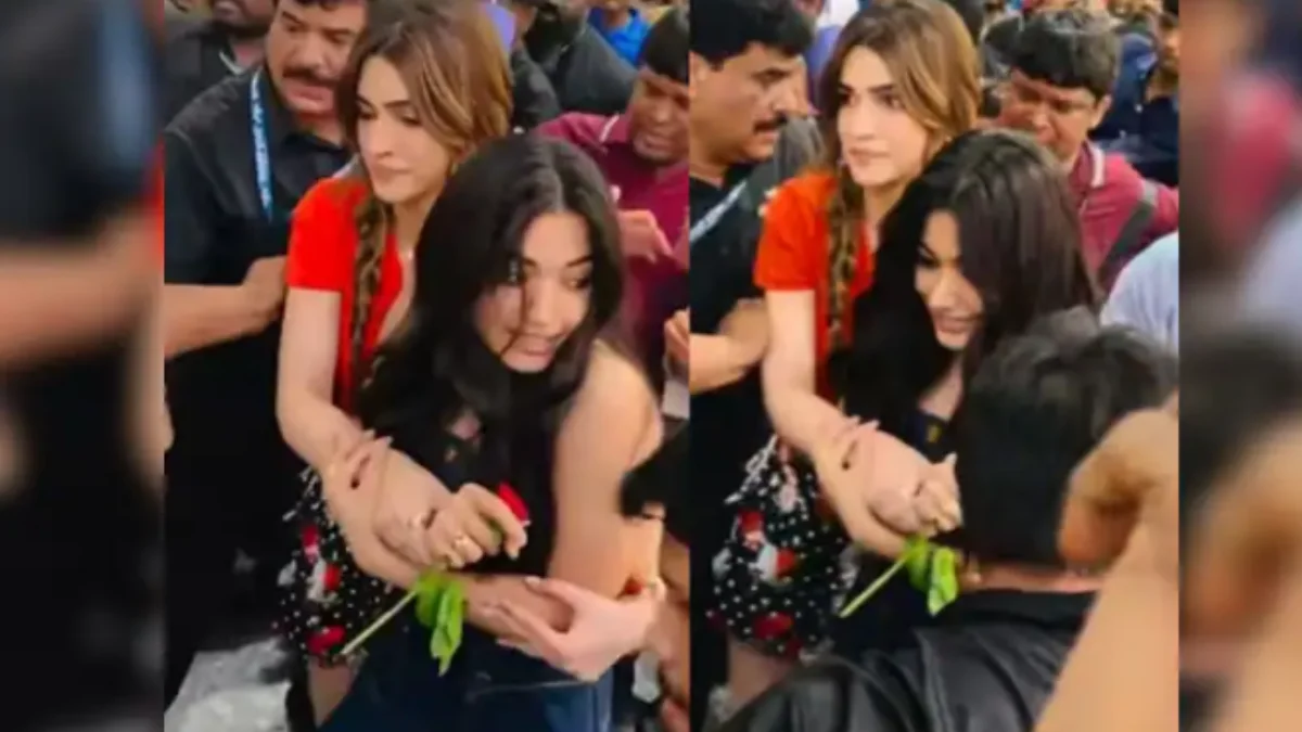 Kriti Sanon protecting Rashmika Mandanna from a crowd during a promotional event at a Pune mall while fans gather around them.
